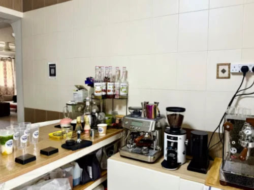 Home-based cafe owner preparing coffee orders in a modern home kitchen setup in a Singapore HDB flat.