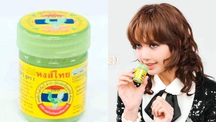 A person holding the iconic green Hong Thai herbal inhaler bottle.