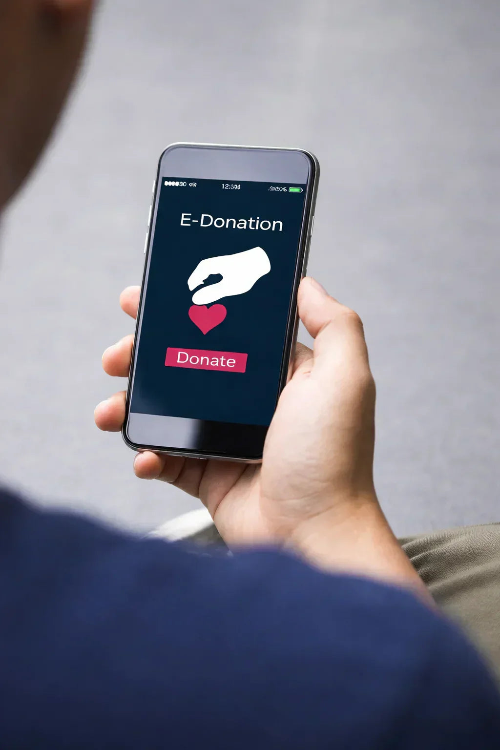 Hand holding a smartphone with an e-donation app open on a gray background